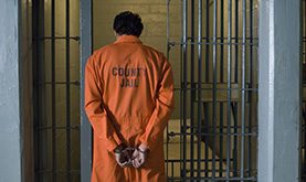 Handcuffed inmate in a jail cell needing local bail bonds in Harris County