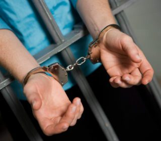 Handcuffed hands through jail bars needing a bail bond in Midtown