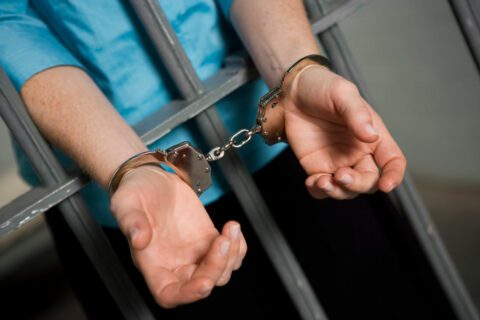 Handcuffed hands through jail bars needing bail in Spring