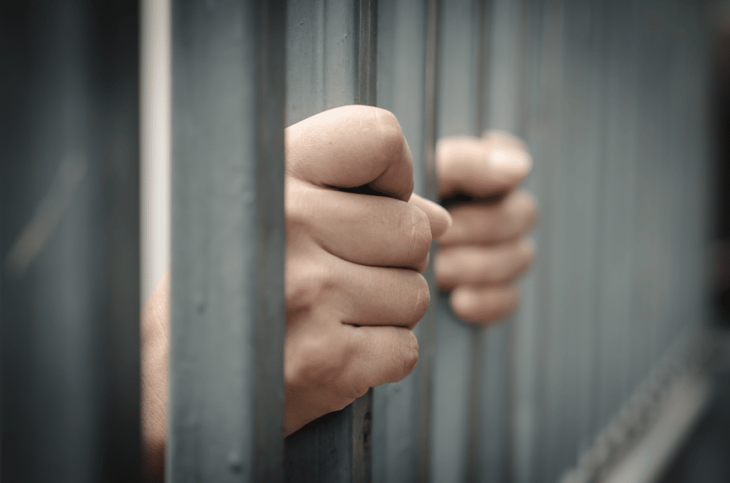 Hand gripping jail bars waiting for 24 hour bail bonds in North Houston