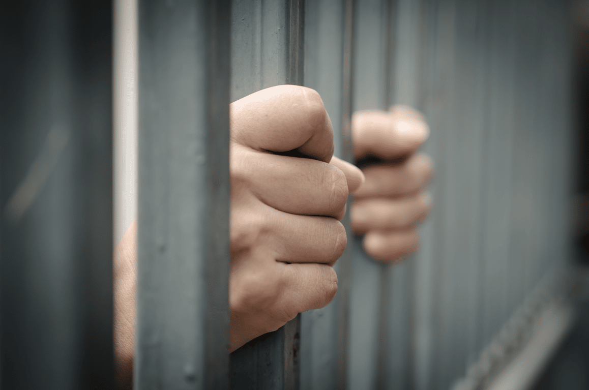 Hand gripping jail bars waiting for bail bonds in Dallas