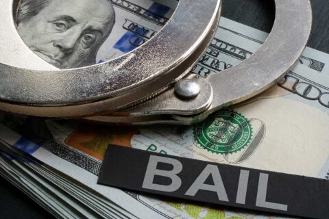 Handcuffs on cash with a bail sign for bail bond loans in Second Ward