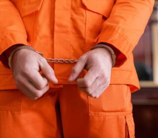 Handcuffed inmate in orange jumpsuit needing a local bail bond in Greenspoint