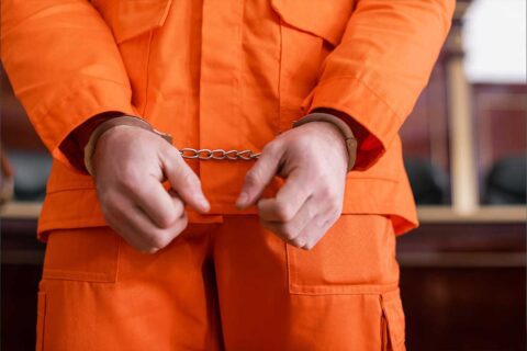 Handcuffed inmate in orange jumpsuit needing 24 hour bail bonds in Sugar Land