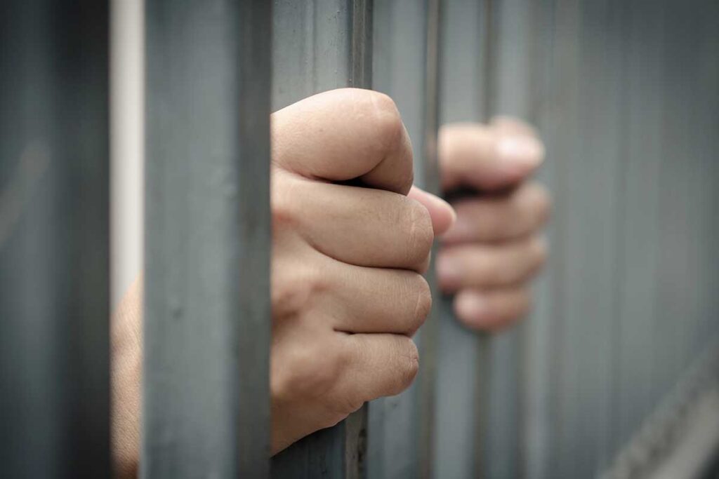 Hand gripping jail bars waiting for a local bail bondsman in Dallas
