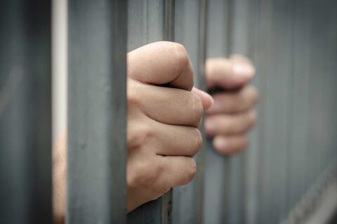 Hand gripping jail bars waiting for a local bail bond in Baytown